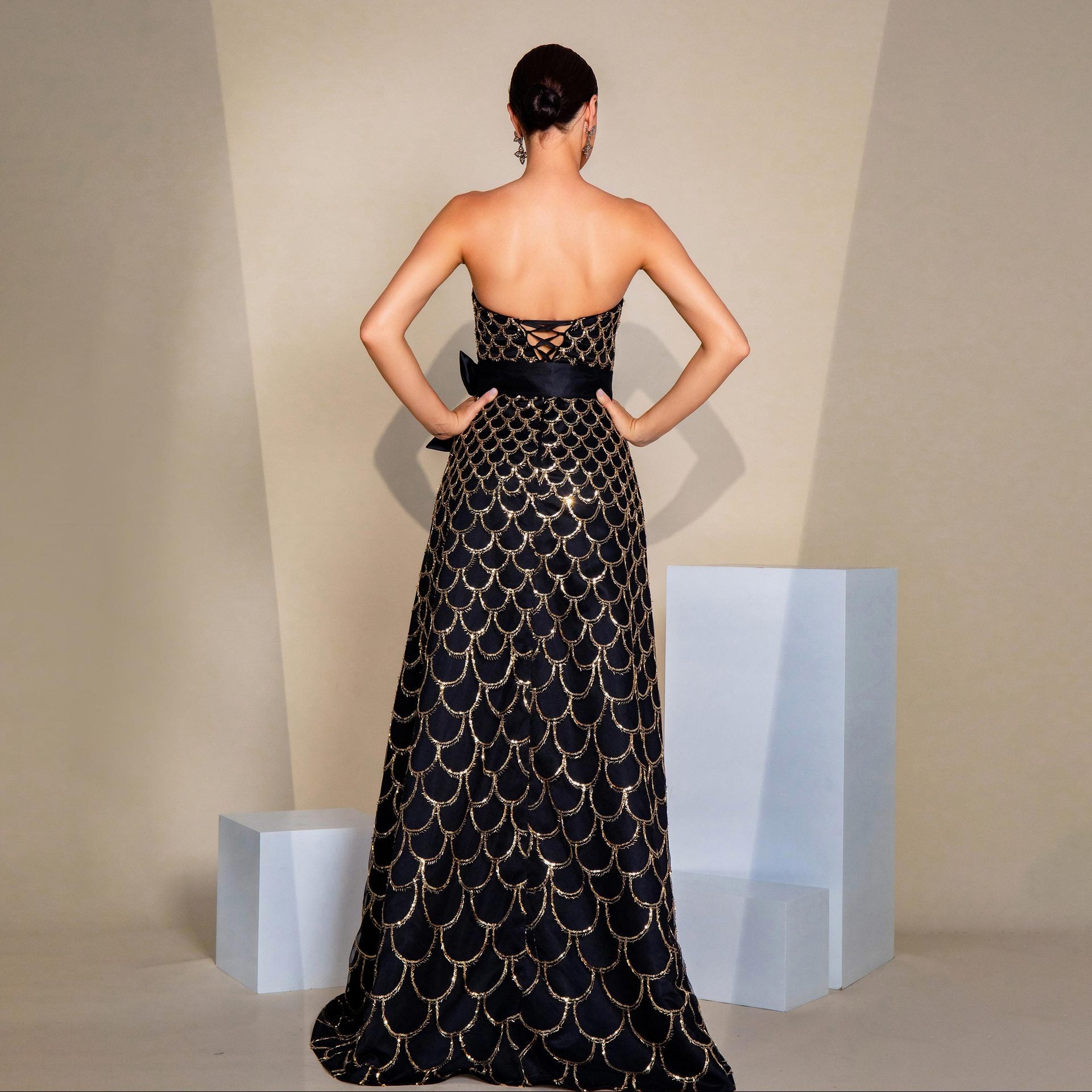 Robe de soirée à sequins, col nu, bustier drapé, taille cintrée et jupe ample.