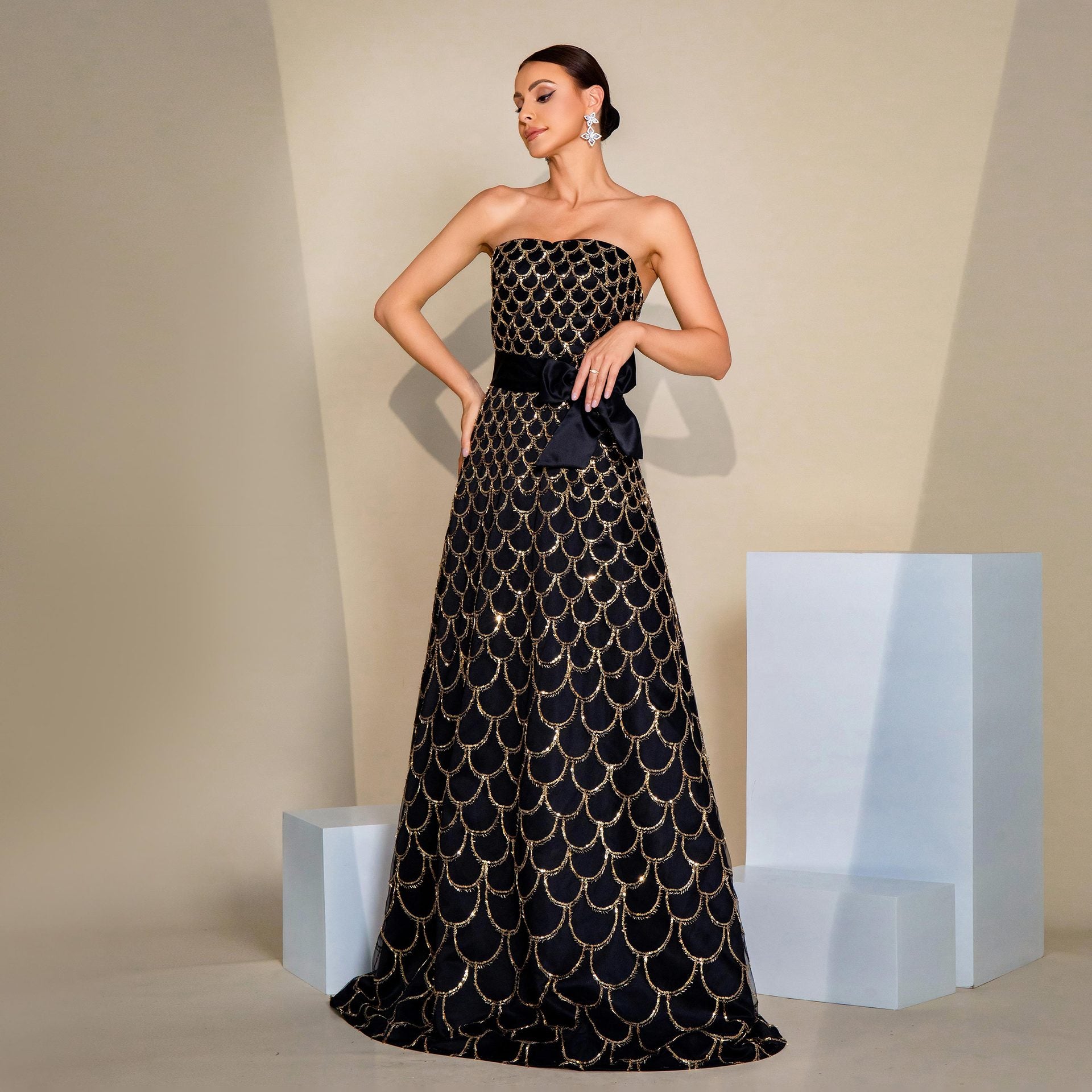 Robe de soirée à sequins, col nu, bustier drapé, taille cintrée et jupe ample.